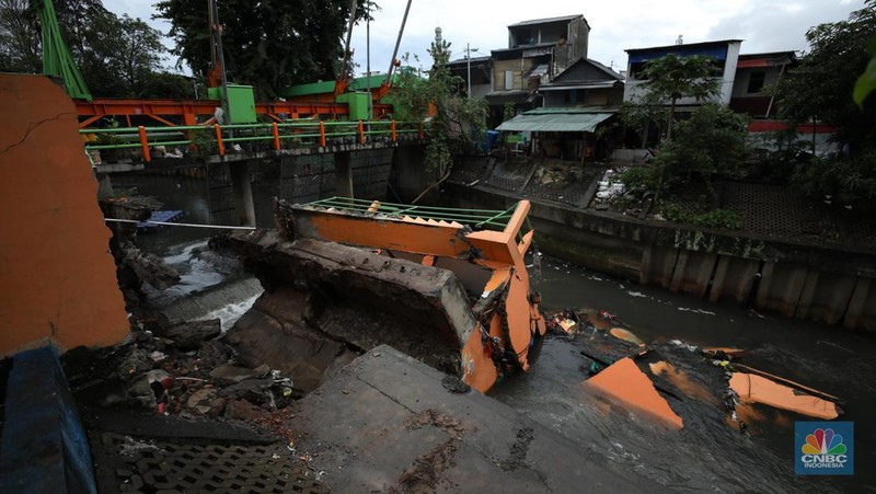 Warga mengamati Pos Pintu Air Palmerah yang jebol di kawasan Palmerah, Jakarta Barat, Selasa (6/2/2024). (CNBC Indonesia/Tri Susilo)