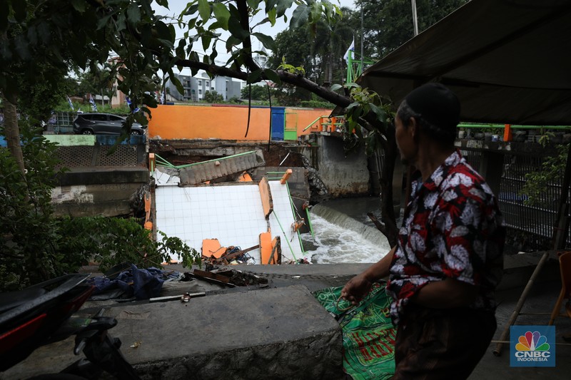 Warga mengamati Pos Pintu Air Palmerah yang jebol di kawasan Palmerah, Jakarta Barat, Selasa (6/2/2024). (CNBC Indonesia/Tri Susilo)