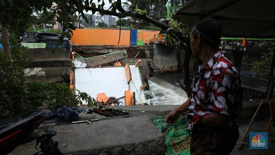 Warga mengamati Pos Pintu Air Palmerah yang jebol di kawasan Palmerah, Jakarta Barat, Selasa (6/2/2024). (CNBC Indonesia/Tri Susilo)