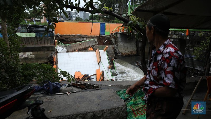 Warga mengamati Pos Pintu Air Palmerah yang jebol di kawasan Palmerah, Jakarta Barat, Selasa (6/2/2024). (CNBC Indonesia/Tri Susilo)