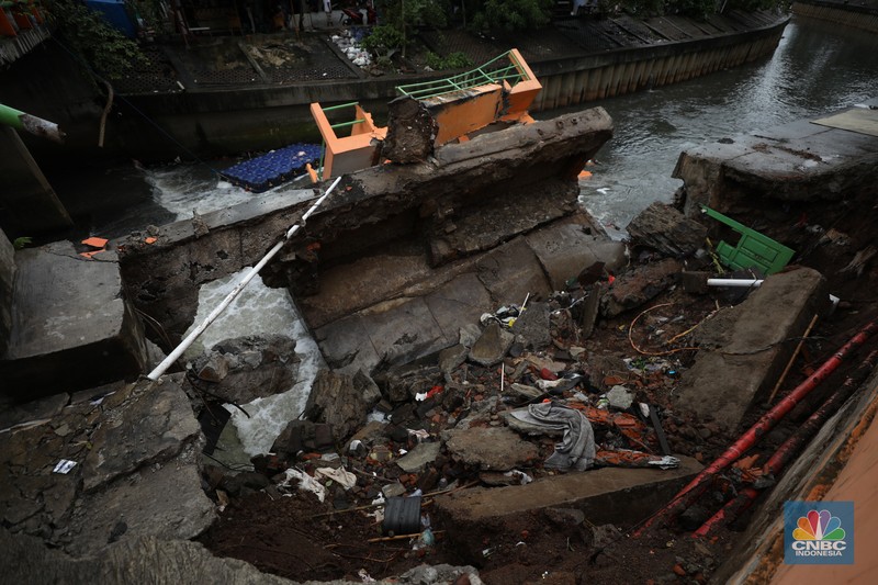 Warga mengamati Pos Pintu Air Palmerah yang jebol di kawasan Palmerah, Jakarta Barat, Selasa (6/2/2024). (CNBC Indonesia/Tri Susilo)