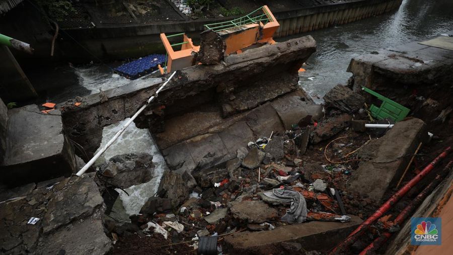 Warga mengamati Pos Pintu Air Palmerah yang jebol di kawasan Palmerah, Jakarta Barat, Selasa (6/2/2024). (CNBC Indonesia/Tri Susilo)