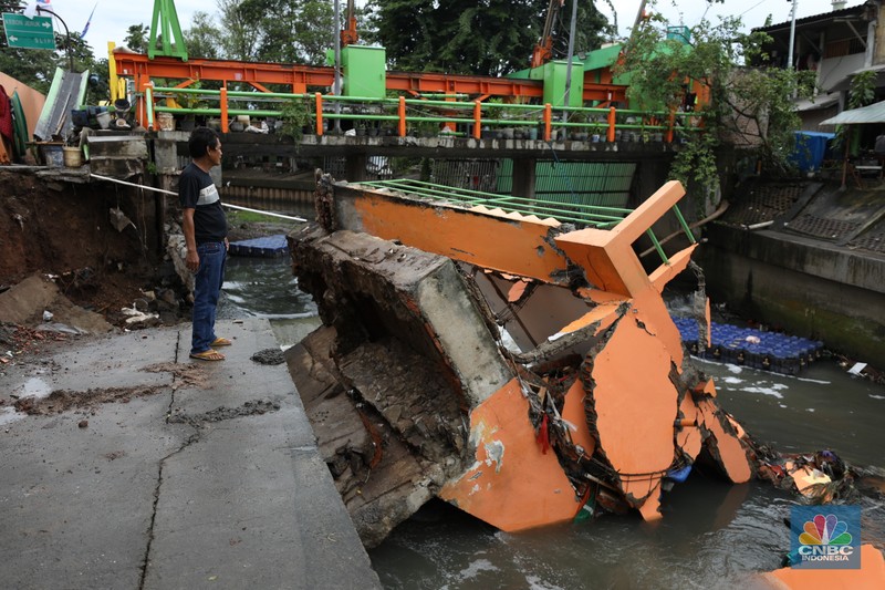 Warga mengamati Pos Pintu Air Palmerah yang jebol di kawasan Palmerah, Jakarta Barat, Selasa (6/2/2024). (CNBC Indonesia/Tri Susilo)
