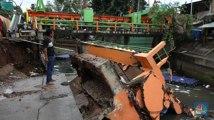 Warga mengamati Pos Pintu Air Palmerah yang jebol di kawasan Palmerah, Jakarta Barat, Selasa (6/2/2024). (CNBC Indonesia/Tri Susilo)
