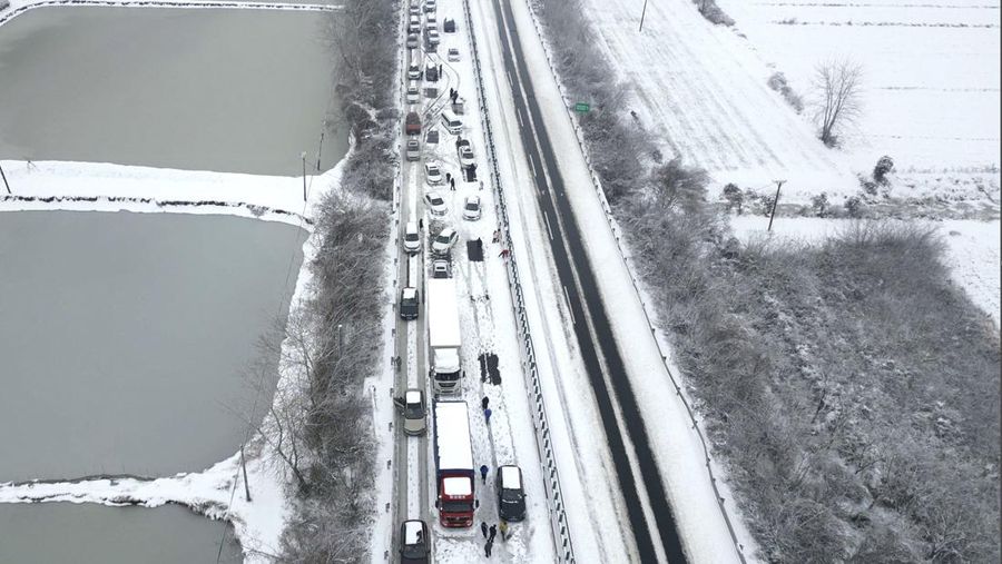 Orang-orang mendorong mobil yang terjebak di jalan raya setelah hujan salju lebat di wilayah tersebut, selama kesibukan perjalanan Festival Musim Semi menjelang Tahun Baru Imlek, di Wuhan, provinsi Hubei, Tiongkok 6 Februari 2024. (China Daily via REUTERS)