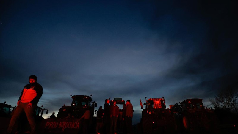 Demonstrators stand next to tractors, as farmers block the AP-7 highway during a protest over price pressures, taxes and green regulation, grievances shared by farmers across Europe, near Girona, Spain, February 6, 2024. REUTERS/Albert Gea