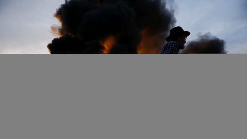 Demonstrators stand next to tractors, as farmers block the AP-7 highway during a protest over price pressures, taxes and green regulation, grievances shared by farmers across Europe, near Girona, Spain, February 6, 2024. REUTERS/Albert Gea