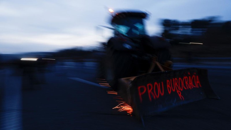 Demonstrators stand next to tractors, as farmers block the AP-7 highway during a protest over price pressures, taxes and green regulation, grievances shared by farmers across Europe, near Girona, Spain, February 6, 2024. REUTERS/Albert Gea
