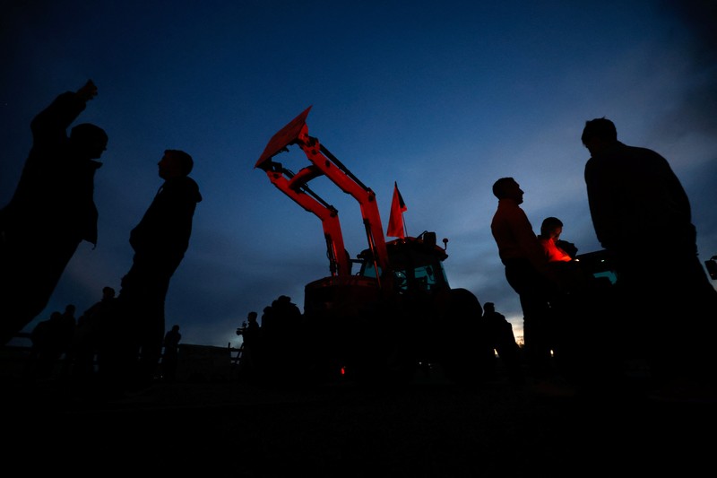 EUROPE-FARMERS/SPAIN Demonstrators stand next to tractors, as farmers block the AP-7 highway during a protest over price pressures, taxes and green regulation, grievances shared by farmers across Europe, near Girona, Spain, February 6, 2024. REUTERS/Albert Gea