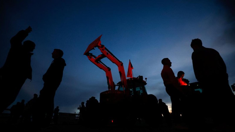 Demonstrators stand next to tractors, as farmers block the AP-7 highway during a protest over price pressures, taxes and green regulation, grievances shared by farmers across Europe, near Girona, Spain, February 6, 2024. REUTERS/Albert Gea