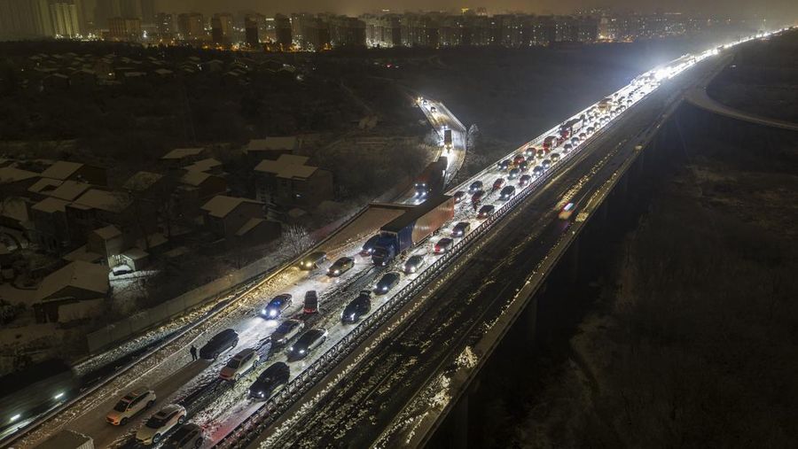 Orang-orang mendorong mobil yang terjebak di jalan raya setelah hujan salju lebat di wilayah tersebut, selama kesibukan perjalanan Festival Musim Semi menjelang Tahun Baru Imlek, di Wuhan, provinsi Hubei, Tiongkok 6 Februari 2024. (China Daily via REUTERS)