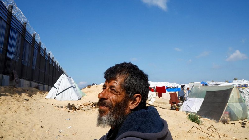 Pengungsi Palestina, Nasser Abu Mustafa, yang meninggalkan rumahnya akibat serangan Israel, melihat saat ia berlindung di perbatasan dengan Mesir, di Rafah di selatan Jalur Gaza, 10 Februari 2024. (REUTERS/Mohammed Salem)