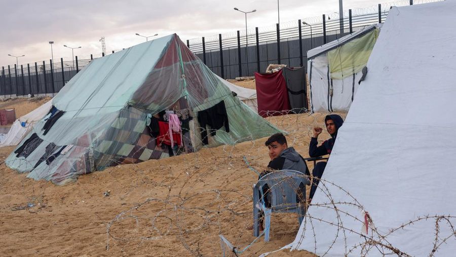 Pengungsi Palestina, yang meninggalkan rumah mereka karena serangan Israel, di tengah konflik yang sedang berlangsung antara Israel dan kelompok Islam Palestina Hamas, duduk di luar tenda di perbatasan dengan Mesir, di tengah kekhawatiran akan serangan darat Israel di Rafah, di Jalur Gaza selatan 18 Februari 2024. REUTERS/Saleh Salem