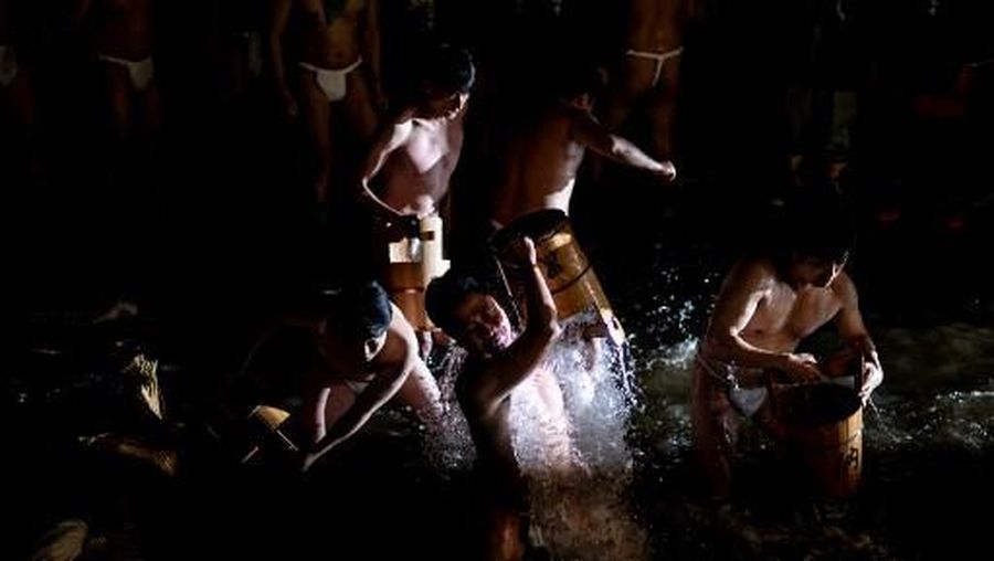 Para pria membersihkan tubuh mereka di sungai selama Festival Sominsai di Kuil Kokuseki-ji di Oshu, Prefektur Iwate, Jepang, pada 17 Februari 2024. (Photo by Philip FONG / AFP)