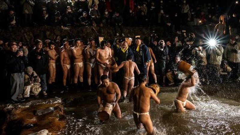 Para pria membersihkan tubuh mereka di sungai selama Festival Sominsai di Kuil Kokuseki-ji di Oshu, Prefektur Iwate, Jepang, pada 17 Februari 2024. (Photo by Philip FONG / AFP)