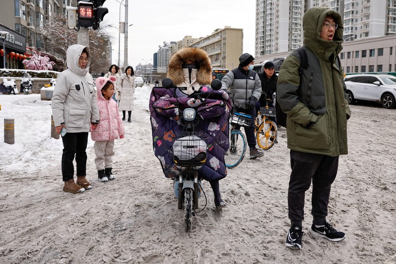 Seorang wanita berjalan di jalan yang tertutup salju setelah hujan salju di Beijing, Cina 21 Februari 2024. (REUTERS/Florence Lo)