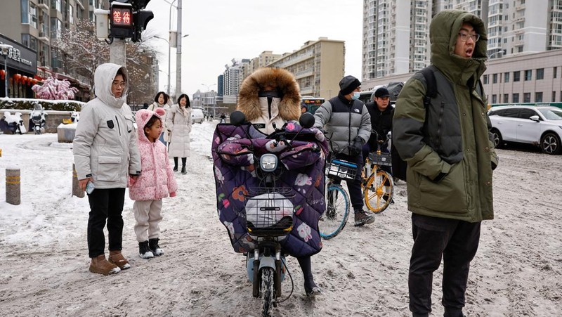 Seorang wanita berjalan di jalan yang tertutup salju setelah hujan salju di Beijing, Cina 21 Februari 2024. (REUTERS/Florence Lo)