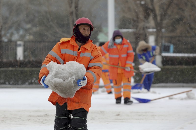 Seorang wanita berjalan di jalan yang tertutup salju setelah hujan salju di Beijing, Cina 21 Februari 2024. (REUTERS/Florence Lo)