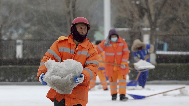 Seorang wanita berjalan di jalan yang tertutup salju setelah hujan salju di Beijing, Cina 21 Februari 2024. (REUTERS/Florence Lo)
