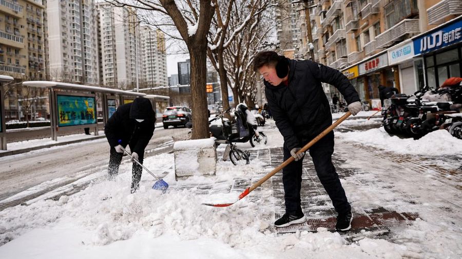 Para pekerja membersihkan salju dari jalan pejalan kaki setelah hujan salju di Beijing, Cina, 21 Februari 2024. (REUTERS/TINGSHU WANG)