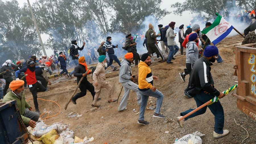 Seorang pria berjalan melewati gas air mata di lokasi protes, ketika para petani berbaris menuju New Delhi untuk menuntut harga tanaman yang lebih baik yang dijanjikan kepada mereka pada tahun 2021, di penghalang Shambhu, perbatasan antara negara bagian Punjab dan Haryana, India, 21 Februari 2024. (REUTERS/Anushree Fadnavis)