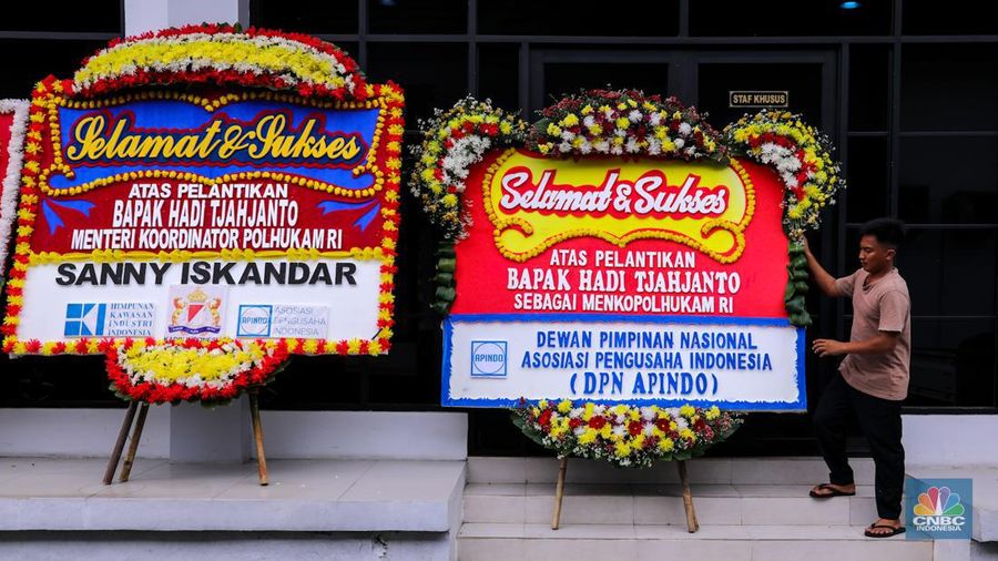 Pekerja menaruh karangan bunga bertuliskan ucapan selamat dan sukses atas pelantikan Marsekal (Purn) TNI Hadi Tjahjanto di kantor Kementrian Koordinator Bidang Politik, Hukum, dan Keamanan RI (Kemenko Polhukam), Jakarta, Rabu (21/2/2024). (CNBC Indonesia/Faisal Rahman)