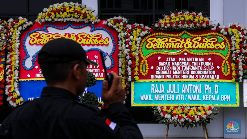 Pekerja menaruh karangan bunga bertuliskan ucapan selamat dan sukses atas pelantikan Marsekal (Purn) TNI Hadi Tjahjanto di kantor Kementrian Koordinator Bidang Politik, Hukum, dan Keamanan RI (Kemenko Polhukam), Jakarta, Rabu (21/2/2024). (CNBC Indonesia/Faisal Rahman)