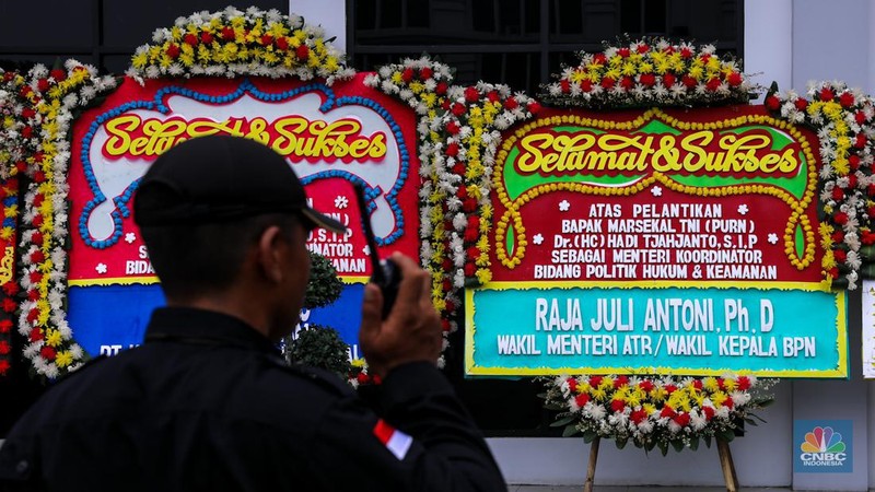 Pekerja menaruh karangan bunga bertuliskan ucapan selamat dan sukses atas pelantikan Marsekal (Purn) TNI Hadi Tjahjanto di kantor Kementrian Koordinator Bidang Politik, Hukum, dan Keamanan RI (Kemenko Polhukam), Jakarta, Rabu (21/2/2024). (CNBC Indonesia/Faisal Rahman)