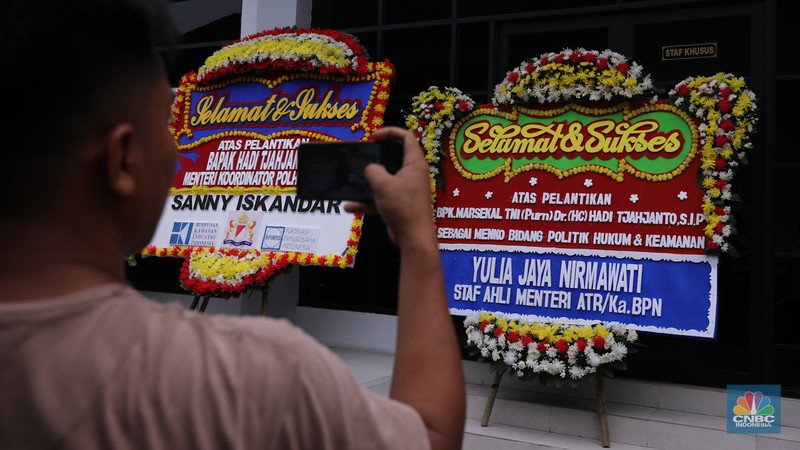 Pekerja menaruh karangan bunga bertuliskan ucapan selamat dan sukses atas pelantikan Marsekal (Purn) TNI Hadi Tjahjanto di kantor Kementrian Koordinator Bidang Politik, Hukum, dan Keamanan RI (Kemenko Polhukam), Jakarta, Rabu (21/2/2024). (CNBC Indonesia/Faisal Rahman)