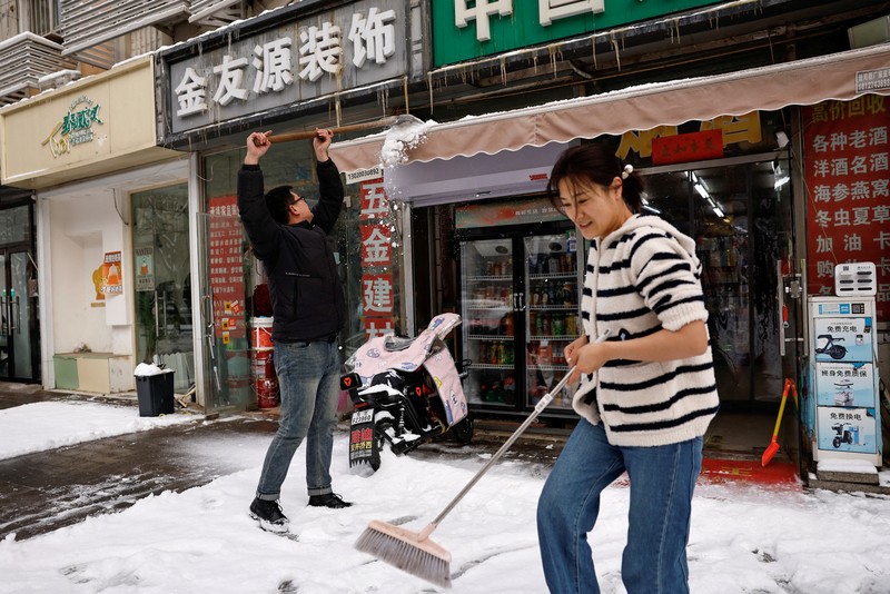 Seorang wanita berjalan di jalan yang tertutup salju setelah hujan salju di Beijing, Cina 21 Februari 2024. (REUTERS/Florence Lo)