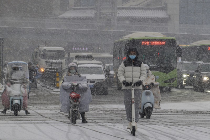 Seorang wanita berjalan di jalan yang tertutup salju setelah hujan salju di Beijing, Cina 21 Februari 2024. (REUTERS/Florence Lo)