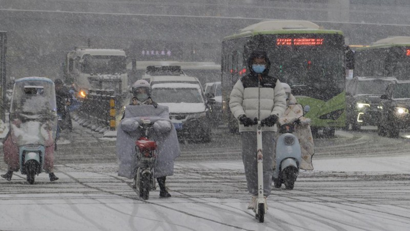 Seorang wanita berjalan di jalan yang tertutup salju setelah hujan salju di Beijing, Cina 21 Februari 2024. (REUTERS/Florence Lo)
