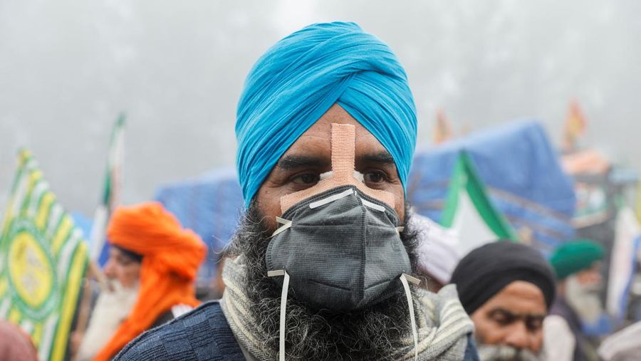 Seorang pria berjalan melewati gas air mata di lokasi protes, ketika para petani berbaris menuju New Delhi untuk menuntut harga tanaman yang lebih baik yang dijanjikan kepada mereka pada tahun 2021, di penghalang Shambhu, perbatasan antara negara bagian Punjab dan Haryana, India, 21 Februari 2024. (REUTERS/Anushree Fadnavis)