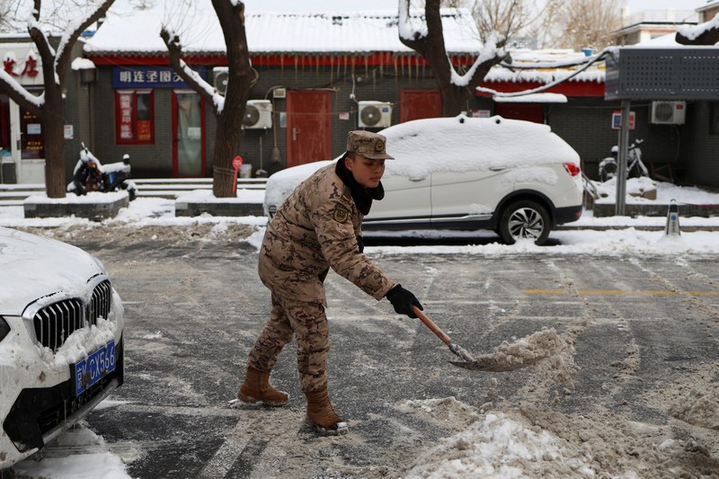 Seorang wanita berjalan di jalan yang tertutup salju setelah hujan salju di Beijing, Cina 21 Februari 2024. (REUTERS/Florence Lo)