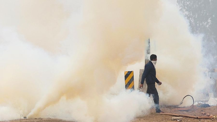 Seorang pria berjalan melewati gas air mata di lokasi protes, ketika para petani berbaris menuju New Delhi untuk menuntut harga tanaman yang lebih baik yang dijanjikan kepada mereka pada tahun 2021, di penghalang Shambhu, perbatasan antara negara bagian Punjab dan Haryana, India, 21 Februari 2024. (REUTERS/Anushree Fadnavis)