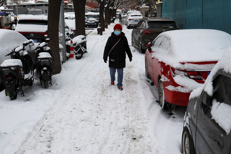 Seorang wanita berjalan di jalan yang tertutup salju setelah hujan salju di Beijing, Cina 21 Februari 2024. (REUTERS/Florence Lo)