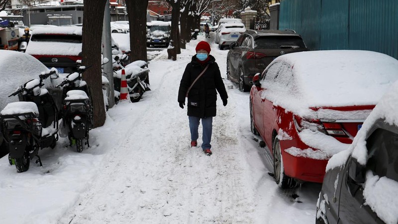 Seorang wanita berjalan di jalan yang tertutup salju setelah hujan salju di Beijing, Cina 21 Februari 2024. (REUTERS/Florence Lo)