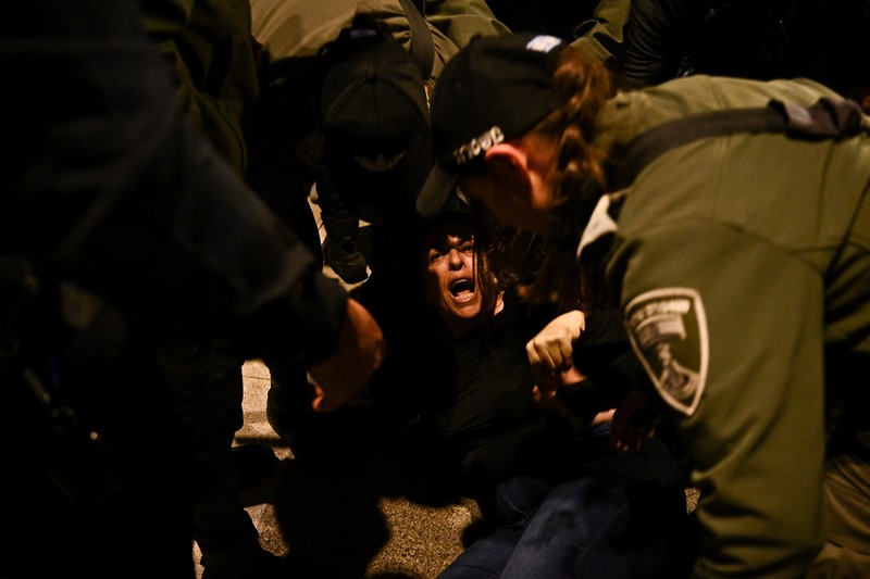 ISRAEL-PALESTINIANS/NETANYAHU-PROTEST People stand on a street as police use water cannons to disperse demonstrators during a protest against Israeli Prime Minister Benjamin Netanyahu's government, amid the ongoing conflict between Israel and the Palestinian Islamist group Hamas from Gaza, in Tel Aviv, Israel, February 24, 2024. REUTERS/Dylan Martinez