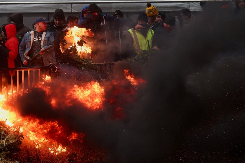 Asap mengepul ketika orang-orang mengambil bagian dalam protes petani Eropa atas tekanan harga, pajak, dan peraturan ramah lingkungan, pada hari pertemuan Menteri Pertanian Uni Eropa di Brussels, Belgia, 26 Februari 2024. (REUTERS/Yves Herman)