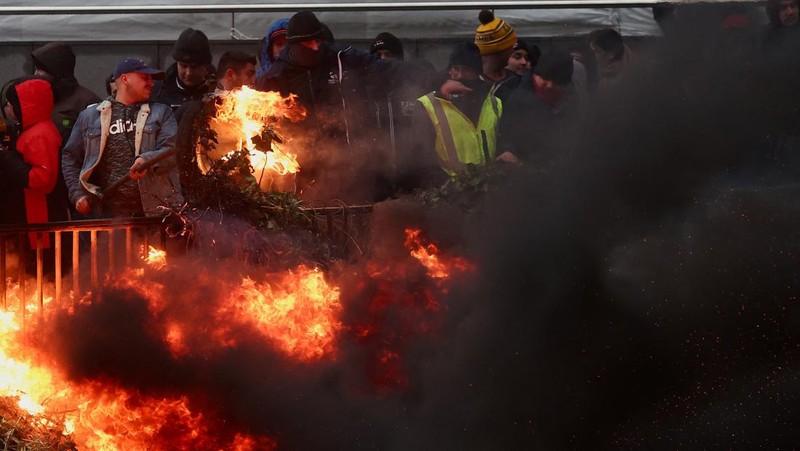 Asap mengepul ketika orang-orang mengambil bagian dalam protes petani Eropa atas tekanan harga, pajak, dan peraturan ramah lingkungan, pada hari pertemuan Menteri Pertanian Uni Eropa di Brussels, Belgia, 26 Februari 2024. (REUTERS/Yves Herman)