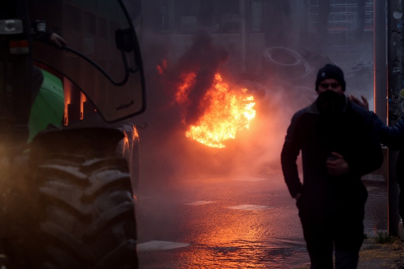 Asap mengepul ketika orang-orang mengambil bagian dalam protes petani Eropa atas tekanan harga, pajak, dan peraturan ramah lingkungan, pada hari pertemuan Menteri Pertanian Uni Eropa di Brussels, Belgia, 26 Februari 2024. (REUTERS/Yves Herman)