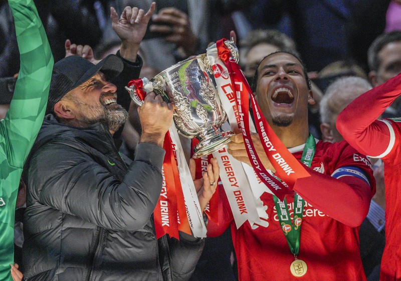 Para pemain Liverpool berpose dengan trofi setelah pertandingan sepak bola final Piala Liga Inggris antara Chelsea dan Liverpool di stadion Wembley, London, pada 25 Februari 2024. Virgil van Dijk mencetak satu-satunya gol di perpanjangan waktu saat Liverpool memenangkan Piala Liga untuk rekor kesepuluh kalinya. (Photo by Glyn KIRK / AFP)