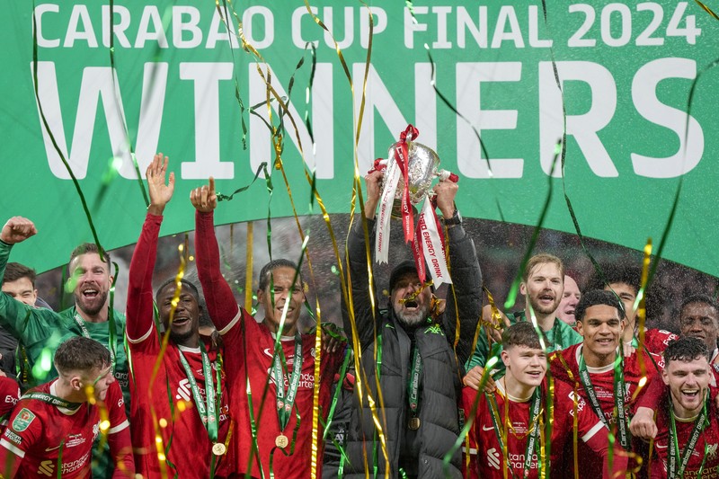 Para pemain Liverpool berpose dengan trofi setelah pertandingan sepak bola final Piala Liga Inggris antara Chelsea dan Liverpool di stadion Wembley, London, pada 25 Februari 2024. Virgil van Dijk mencetak satu-satunya gol di perpanjangan waktu saat Liverpool memenangkan Piala Liga untuk rekor kesepuluh kalinya. (Photo by Glyn KIRK / AFP)