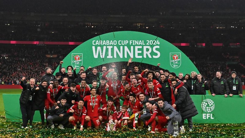 Para pemain Liverpool berpose dengan trofi setelah pertandingan sepak bola final Piala Liga Inggris antara Chelsea dan Liverpool di stadion Wembley, London, pada 25 Februari 2024. Virgil van Dijk mencetak satu-satunya gol di perpanjangan waktu saat Liverpool memenangkan Piala Liga untuk rekor kesepuluh kalinya. (Photo by Glyn KIRK / AFP)