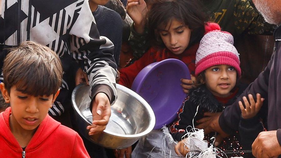 Anak-anak Palestina yang terlantar menunggu untuk menerima makanan gratis di tenda kamp, ​​di tengah kekurangan makanan, saat konflik antara Israel dan Hamas berlanjut, di Rafah di selatan Jalur Gaza, 27 Februari 2024. (REUTERS/Ibraheem Abu Mustafa)