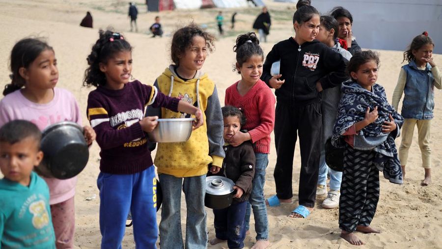 Anak-anak Palestina yang terlantar menunggu untuk menerima makanan gratis di tenda kamp, ​​di tengah kekurangan makanan, saat konflik antara Israel dan Hamas berlanjut, di Rafah di selatan Jalur Gaza, 27 Februari 2024. (REUTERS/Ibraheem Abu Mustafa)