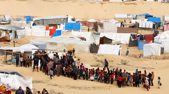 Pengungsi Palestina menunggu untuk menerima makanan gratis di tenda kamp, ​​di tengah kekurangan pangan, saat konflik antara Israel dan Hamas berlanjut, di Rafah di selatan Jalur Gaza, 27 Februari 2024. (REUTERS/Ibraheem Abu Mustafa)