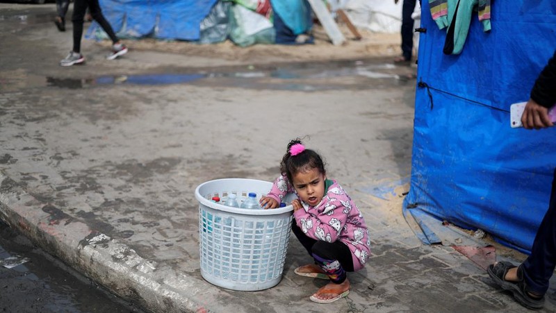 Anak-anak Palestina yang terlantar menunggu untuk menerima makanan gratis di tenda kamp, ​​di tengah kekurangan makanan, saat konflik antara Israel dan Hamas berlanjut, di Rafah di selatan Jalur Gaza, 27 Februari 2024. (REUTERS/Ibraheem Abu Mustafa)