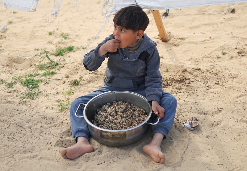 Anak-anak Palestina yang terlantar menunggu untuk menerima makanan gratis di tenda kamp, di tengah kekurangan makanan, saat konflik antara Israel dan Hamas berlanjut, di Rafah di selatan Jalur Gaza, 27 Februari 2024. Anak-anak Palestina yang terlantar menunggu untuk menerima makanan gratis di tenda kamp, di tengah kekurangan makanan, saat konflik antara Israel dan Hamas berlanjut, di Rafah di selatan Jalur Gaza, 27 Februari 2024. (REUTERS/Ibraheem Abu Mustafa)