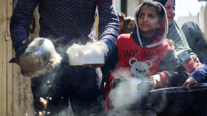 Anak-anak Palestina menunggu untuk menerima makanan yang dimasak oleh dapur amal di tengah kekurangan pasokan makanan, ketika konflik yang sedang berlangsung antara Israel dan kelompok Islam Palestina Hamas berlanjut, di Rafah, di selatan Jalur Gaza, 5 Maret 2024. (REUTERS/Mohammed Salem)